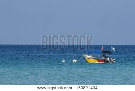 Boat at crystal clear waters Perhentian Kecil Island beach Terengganu Malaysia.