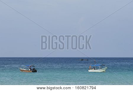 Boat at crystal clear waters Perhentian Kecil Island beach Terengganu Malaysia.