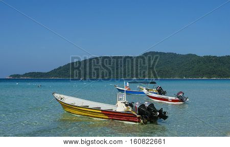 Boat at crystal clear waters Perhentian Kecil Island beach Terengganu Malaysia.