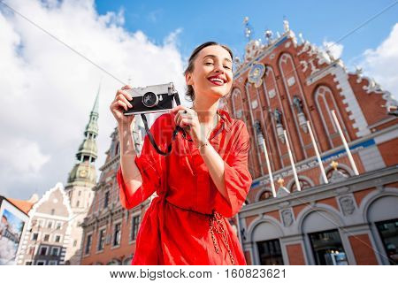 Portrait of a young female tourist with photo camera on the main old town square in Riga. Woman having great vacations in Latvia