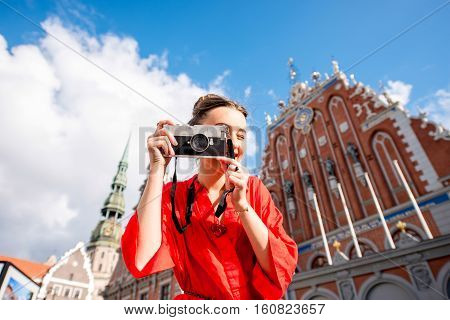 Portrait of a young female tourist with photo camera on the main old town square in Riga. Woman having great vacations in Latvia