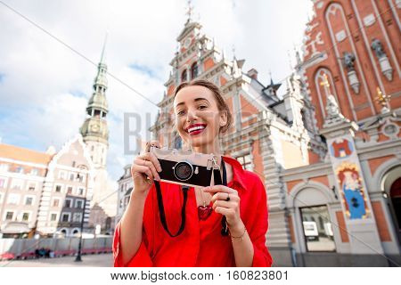 Portrait of a young female tourist with photo camera on the main old town square in Riga. Woman having great vacations in Latvia