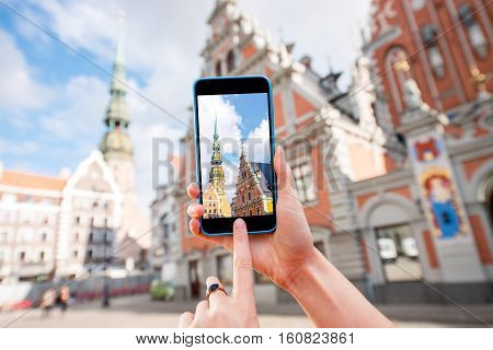 Photographing with smart phone famous houses of Blackheads and Peter church in the old town's center in Riga