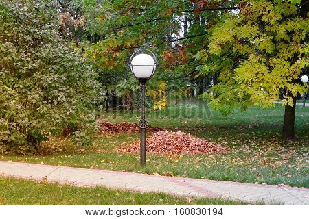Autumn landscape: the Park in the bushes and trees covered with yellow leaves the leaves lying on the grass. The landscape is decorated with beautiful lantern . Перевести вGoogleBing
