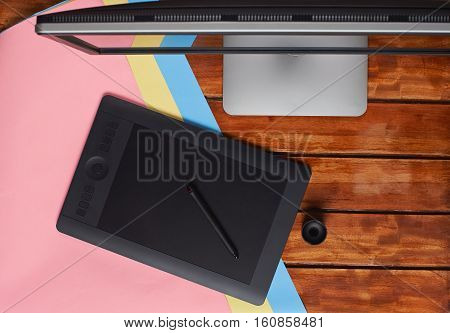 Top of designer wooden table with colourful paper and grapic table and big screen