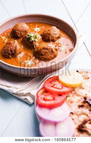 malai kofta curry - classic North Indian dish. vegetarian alternative to meatballs served with tandoori roti or indian bread and green salad, selective focus