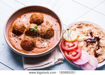 malai kofta curry - classic North Indian dish. vegetarian alternative to meatballs served with tandoori roti or indian bread and green salad, selective focus