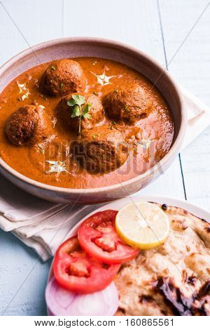 malai kofta curry - classic North Indian dish. vegetarian alternative to meatballs served with tandoori roti or indian bread and green salad, selective focus