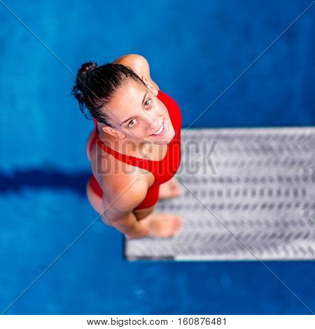 Female diver standing on the jumping board. Preparing to jump into the pool