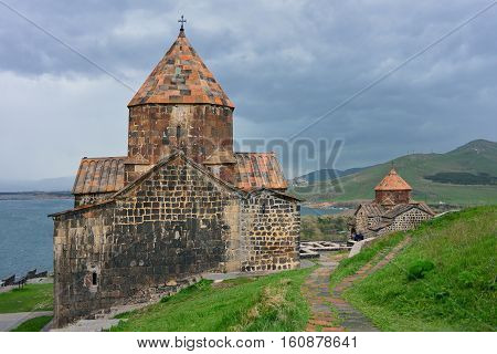 The tourists visit Sevanavank Monastery located on Sevan Peninsula among the bright green hills