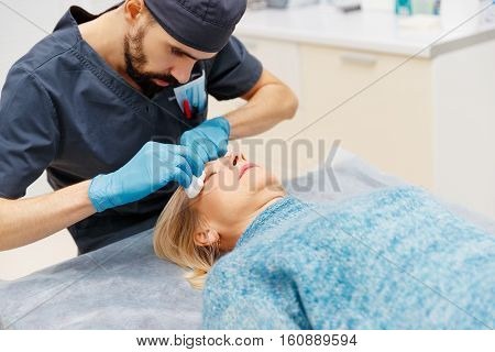 marking the face of an elderly woman old of plastic surgery at a reception at the doctor