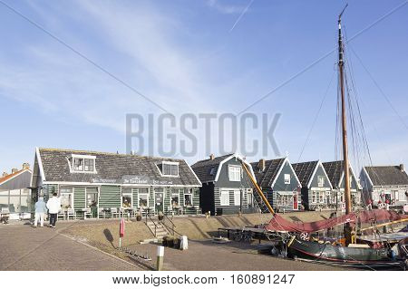 Marken, Netherlands, 22 november 2016: old sailing vessel and tourists in harbor of dutch village Marken and old wooden houses
