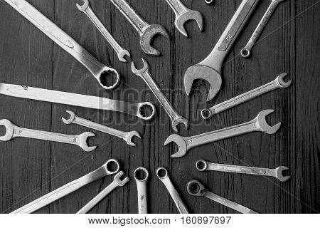 Many wrenchs on the black wooden background.