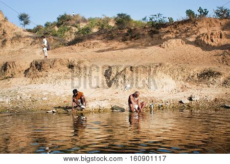 CHITRAKOOT, INDIA - DEC 28, 2012: Morning washing of poor men on the river bank in the rural landscape on December 28, 2012. Population of Chitrakoot is 22294. By the legend Lord Rama lived here