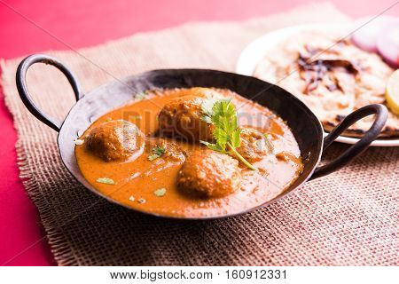 Freshly cooked spicy potato curry in frying pan or Hot and spicy Dum aloo served with tandoori roti or naan or indian bread or chapati and green salad, selective focus