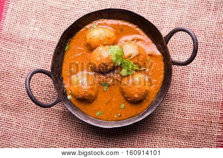 Freshly cooked spicy potato curry in frying pan or Hot and spicy Dum aloo served with tandoori roti or naan or indian bread or chapati and green salad, selective focus