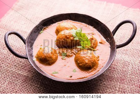 Freshly cooked spicy potato curry in frying pan or Hot and spicy Dum aloo served with tandoori roti or naan or indian bread or chapati and green salad, selective focus