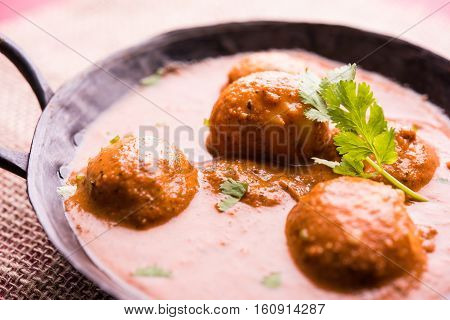 Freshly cooked spicy potato curry in frying pan or Hot and spicy Dum aloo served with tandoori roti or naan or indian bread or chapati and green salad, selective focus