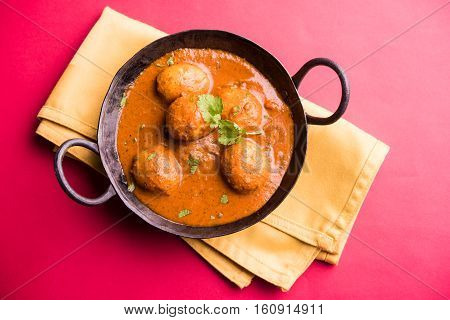 Freshly cooked spicy potato curry in frying pan or Hot and spicy Dum aloo served with tandoori roti or naan or indian bread or chapati and green salad, selective focus