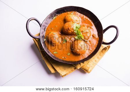 Freshly cooked spicy potato curry in frying pan or Hot and spicy Dum aloo served with tandoori roti or naan or indian bread or chapati and green salad, selective focus