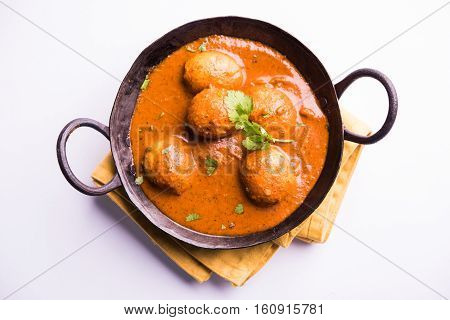 Freshly cooked spicy potato curry in frying pan or Hot and spicy Dum aloo served with tandoori roti or naan or indian bread or chapati and green salad, selective focus