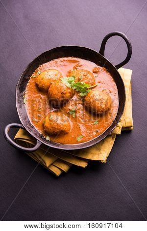 Freshly cooked spicy potato curry in frying pan or Hot and spicy Dum aloo served with tandoori roti or naan or indian bread or chapati and green salad, selective focus