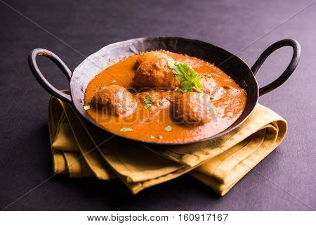 Freshly cooked spicy potato curry in frying pan or Hot and spicy Dum aloo served with tandoori roti or naan or indian bread or chapati and green salad, selective focus