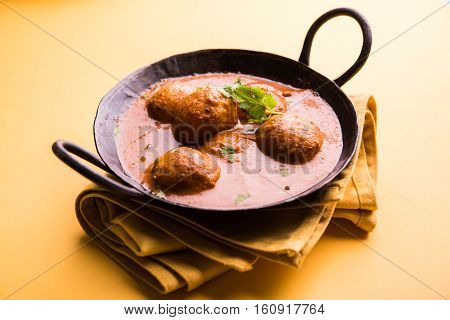 Freshly cooked spicy potato curry in frying pan or Hot and spicy Dum aloo served with tandoori roti or naan or indian bread or chapati and green salad, selective focus