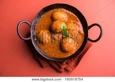 Freshly cooked spicy potato curry in frying pan or Hot and spicy Dum aloo served with tandoori roti or naan or indian bread or chapati and green salad, selective focus