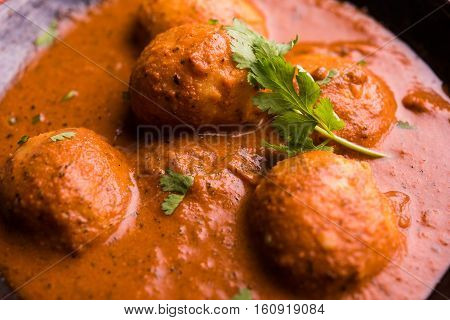 Freshly cooked spicy potato curry in frying pan or Hot and spicy Dum aloo served with tandoori roti or naan or indian bread or chapati and green salad, selective focus