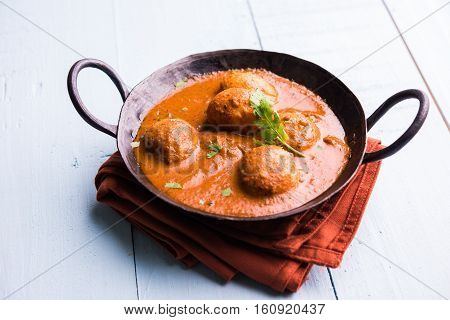 Freshly cooked spicy potato curry in frying pan or Hot and spicy Dum aloo served with tandoori roti or naan or indian bread or chapati and green salad, selective focus