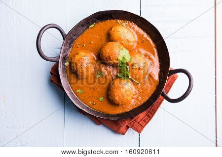 Freshly cooked spicy potato curry in frying pan or Hot and spicy Dum aloo served with tandoori roti or naan or indian bread or chapati and green salad, selective focus