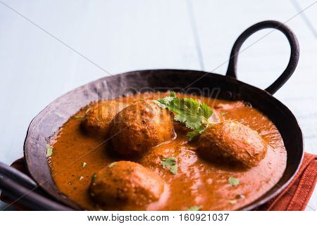 Freshly cooked spicy potato curry in frying pan or Hot and spicy Dum aloo served with tandoori roti or naan or indian bread or chapati and green salad, selective focus
