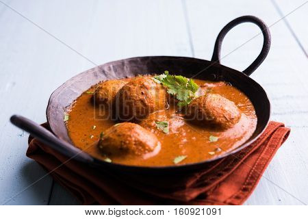 Freshly cooked spicy potato curry in frying pan or Hot and spicy Dum aloo served with tandoori roti or naan or indian bread or chapati and green salad, selective focus