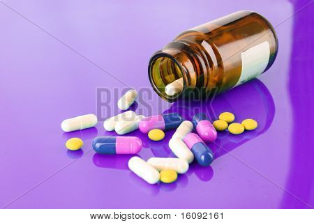 Botella de píldora con pastillas de colores a puple