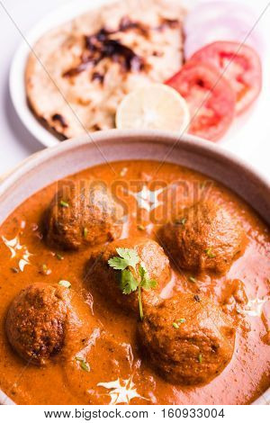 malai kofta curry - classic North Indian dish. vegetarian alternative to meatballs served with tandoori roti or indian bread and green salad, selective focus