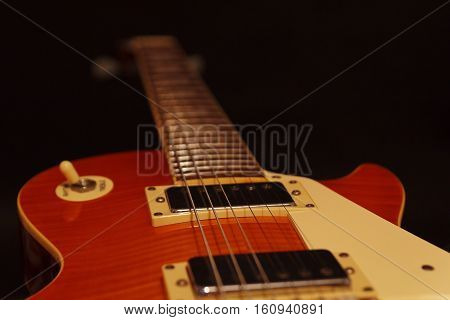 Solid body electric guitar closeup on the black background. Selective focus.
