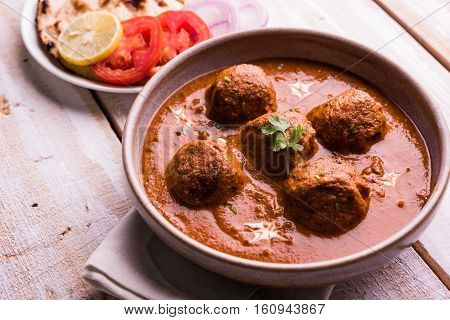 malai kofta curry - classic North Indian dish. vegetarian alternative to meatballs served with tandoori roti or indian bread and green salad, selective focus