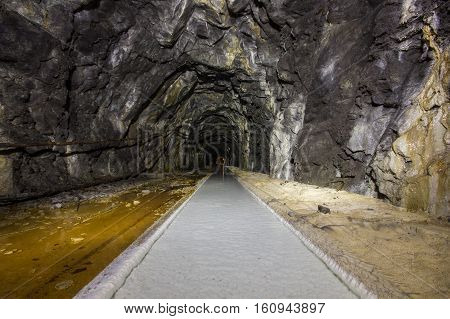 Old abandoned iron ore mine shaft tunnel with rails