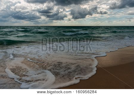 A wavy ocean water surface under cloudy sky.