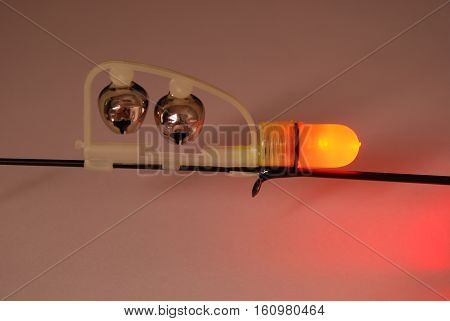 Fishing green rattle and red LED power indicator (attached to the tip of the feeder) isolated on gray backgtound. Clipping path