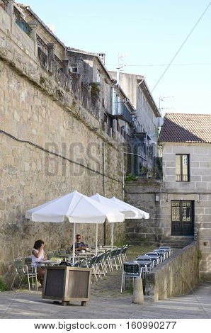 TUI, SPAIN - AUGUST 7, 2016: Two people at an outdoor coffee bar next to a stone wall in Tui a town of the province of Pontevedra in Galicia Spain.
