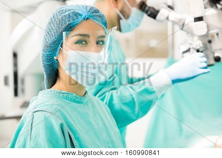 Beautiful Hispanic young female surgeon making eye contact while operating on a patient in a hospital