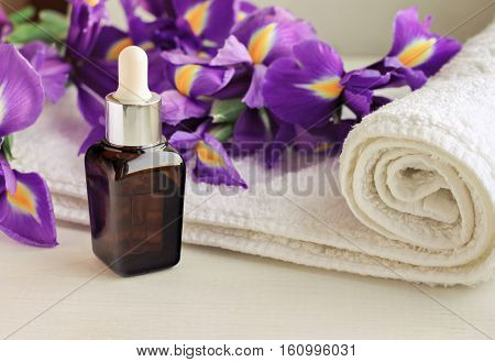 Flower essence dropper bottle,violet Iris, white terry towel wrap.Floral decorated spa set. Warm toned.
