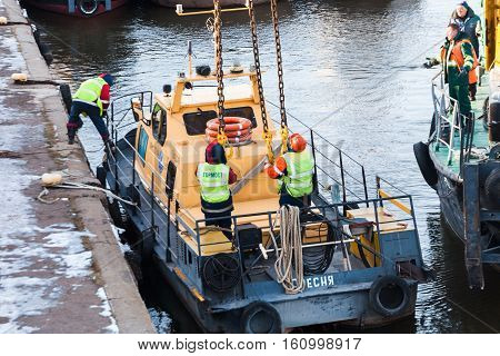 MOSCOW, RUSSIA - NOVEMBER 11, 2016: State Unitary Enterprise Mosvodostok performs recovery vessels on coastal winter parking. Workers slingers hooked to the vehicle chain slings.