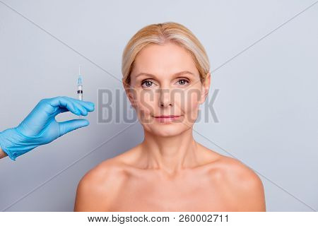 Portrait Of Calm Serious Aged Woman Ready For Neoplastic Correction Lifting, Hand In Latex Gloves Sh