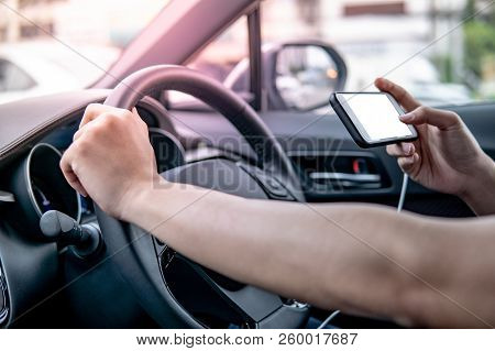 Male Driver Hand Holding On Steering Wheel Using Smartphone For Gps Navigation. Mobile Phone Mountin