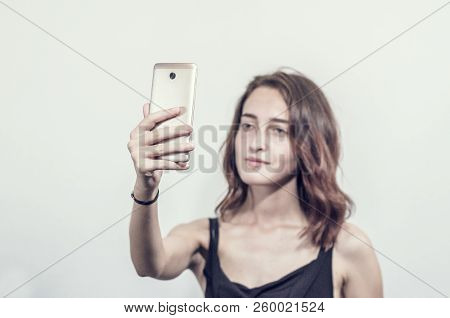 Beautiful Young Girl Holding A Phone. Makes Photos, Selfies