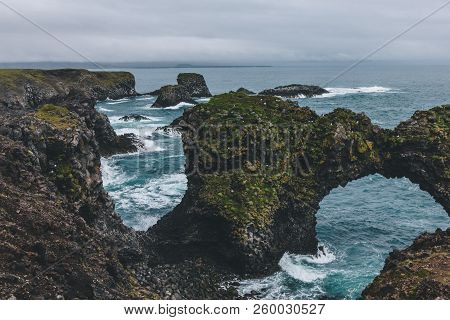 Scenic Mossy Cliffs In Front Of Blue Ocean In Arnarstapi, Iceland On Cloudy Day