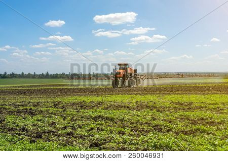 Self-propelled Sprayer Works On A Field Under A Blue Sky With Clouds